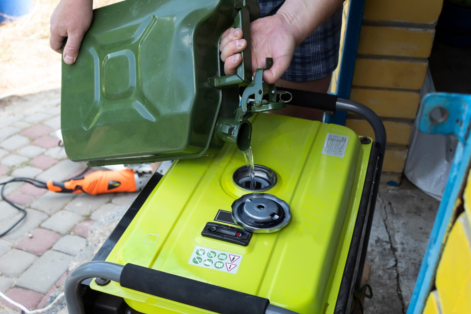 Person pouring fuel from a gas can into a portable generator's tank.