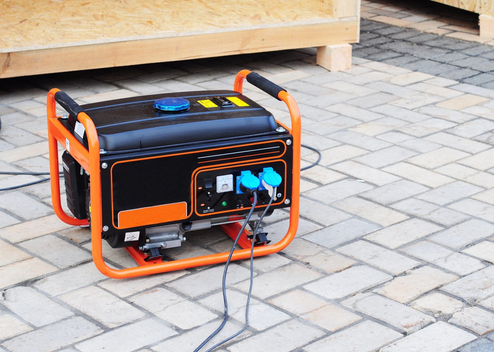 Portable generator with an orange frame set up on a paver patio.